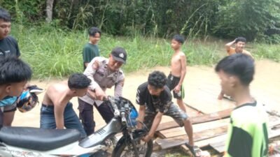 Bhabinkamtibmas Bantu Pengguna Jalan Tergenang Air